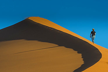 Woman hiking up the giant Sand Dune 45, Sossusvlei, Namib-Naukluft National Park, Namibia, Africa