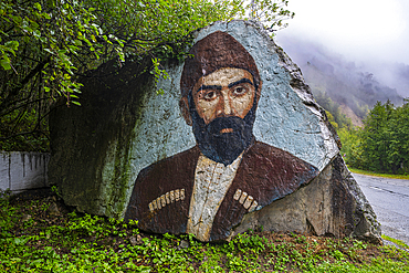 Artist creating a mural on a large rock in North Ossetia, showcasing local culture and heritage in Russia