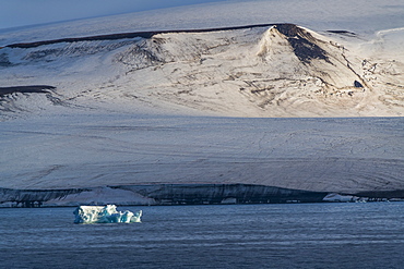 Iceberg floating in front of flat table mountains covered with ice, Franz Josef Land archipelago, Arkhangelsk Oblast, Arctic, Russia, Europe