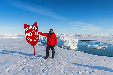 Man standing by sign at North Pole, Arctic