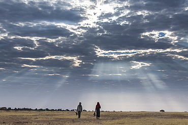 Bedouin children walking under a dramatic sky in the Sahel, Chad, Africa