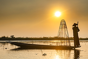 Fisherman at Inle Lake with traditional Intha conical net at sunset, fishing net, leg rowing style, Intha people, Inle Lake, Shan state, Myanmar (Burma), Asia