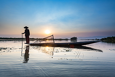 Fisherman at Inle Lake with traditional Intha conical net at sunset, fishing net, leg rowing style, Intha people, Inle Lake, Shan state, Myanmar (Burma), Asia