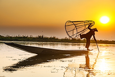 Fisherman at Inle Lake with traditional Intha conical net at sunset, fishing net, leg rowing style, Intha people, Inle Lake, Shan state, Myanmar (Burma), Asia