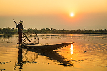 Fisherman at Inle Lake with traditional Intha conical net at sunset, fishing net, leg rowing style, Intha people, Inle Lake, Shan state, Myanmar (Burma), Asia