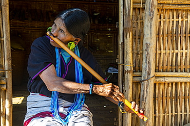 Chin woman with spiderweb tattoo blowing a flute with her nose, Kanpelet, Chin state, Myanmar (Burma), Asia