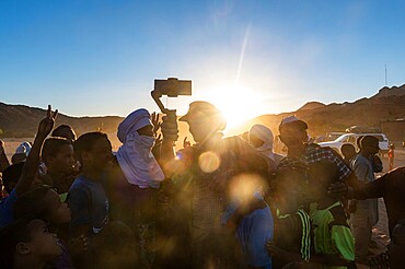 Backlight of a crowd of children and Tuareg men, Oasis of Timia, Air Mountains, Niger, Africa