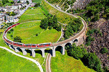 Aerial of a Train crossing the Brusio spiral viaduct, UNESCO World Heritage Site, Rhaetian Railway, Switzerland, Europe