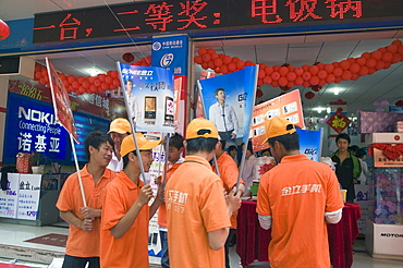 China young men hired to advertise goods outside an electronics shop in kunming, yunnan province