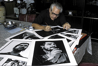 Roberto salas with pictures of 'che' guevara, cuba. The photographer salas looking at his world-famous prints of the guerilla leader, taken in the 1960s