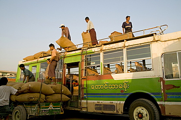 Myanmar (burma) loading sacks on to a bus at mandalay coach station