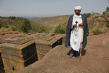 Orthodox priest hold cross at the ancient sunken rock-hewn church of St. George in Lalibela, Ethiopia, Africa