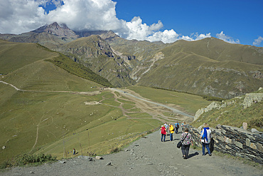 Tourists near the Gergeti Holy Trinity Church by the river Chkheri, under Mount Kazbegi at an elevation of 2170 meters in the Caucasus, Georgia, Central Asia, Asia