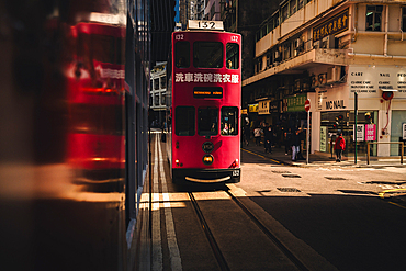 An artistic photograph of a pink Hong Kong Tram going through a strip of Sunlight as it comes into Hong Kong