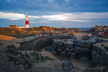 Portland Bill Lighthouse at sunset with remnants of limestone quarry in the foreground, Portland, Dorset, UK