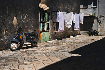 Corfu Old Town and black Vespa motorbike with hanging laundry.
