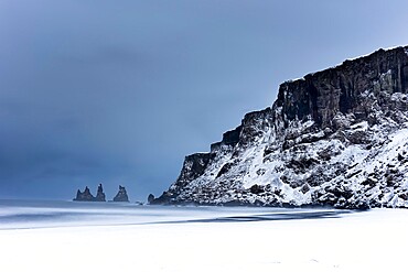 Black basalt sea stacks and snow covered black sand beach, Vik, Iceland, Polar Regions