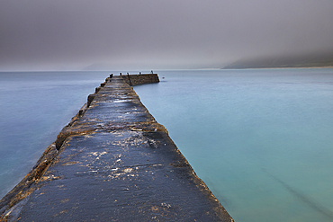 A misty, murky dawn view of the breakwater at Sennen Cove; on the Atlantic coast near Land's End, in the far west of Cornwall, Great Britain.