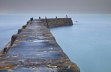 A misty, murky dawn view of the breakwater at Sennen Cove; on the Atlantic coast near Land's End, in the far west of Cornwall, Great Britain.