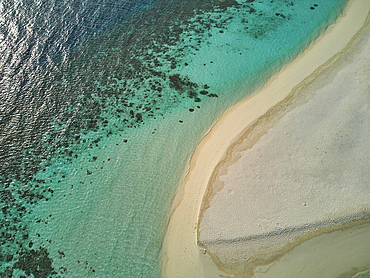 A drone view of a sandy tropical beach, with a lagoon fringed by a coral reef; Havodda Island, Gaafu Dhaalu atoll, in the far south of the Maldives, Indian Ocean.