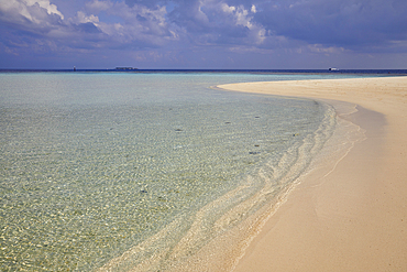 Pristine shallow waters lap against the white coral sand of a tropical beach; Havodda Island, in the far south of the Maldives, Gaafu Dhaalu atoll, Indian Ocean.
