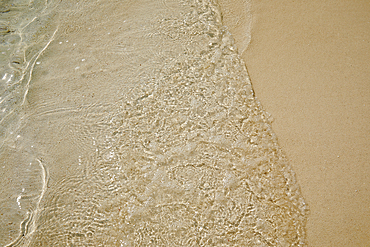 Pristine shallow waters lap against the white coral sand of a tropical beach; Havodda Island, in the far south of the Maldives, Gaafu Dhaalu atoll, Indian Ocean.