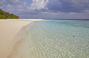 Pristine shallow waters lap against the white coral sand of a tropical beach; Havodda Island, in the far south of the Maldives, Gaafu Dhaalu atoll, Indian Ocean.
