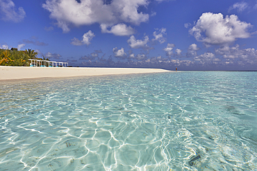 Pristine shallow waters lap against the white coral sand of a tropical beach; Havodda Island, in the far south of the Maldives, Gaafu Dhaalu atoll, Indian Ocean.