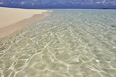 Pristine shallow waters lap against the white coral sand of a tropical beach; Havodda Island, in the far south of the Maldives, Gaafu Dhaalu atoll, Indian Ocean.