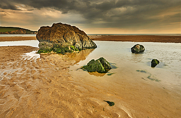 A low tide view of rocks, rippled sand and pools of water on the beach at Bigbury-on-Sea, on the south coast of Devon, Great Britain.