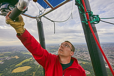 A balloon pilot adjusting the burning gas jets that heat air inside the balloon, during the Bristol International Balloon Fiesta, England, United Kingdom, Europe