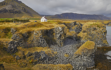 A classic view of the basalt lava cliffs on the coast at the village of Arnastapi, backed by the mountains of Snaefellsjokull, Snaefellsjokull National Park, Snaefellsness peninsula, west coast of Iceland, Polar Regions