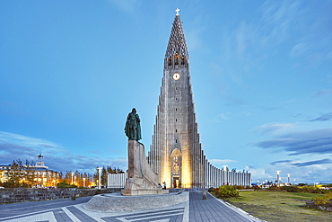 A dusk view of the spire of Hallgrimskirkja Church, fronted by a statue of Leifur Eriksson, founder of Iceland, in central Reykjavik, Iceland, Polar Regions