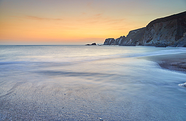 A dusk view of surf surging ashore at Ayrmer Cove, a remote cove near Kingsbridge, south coast of Devon, England, United Kingdom, Europe