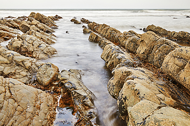 A rising tide brings the Atlantic around and over shoreline rocks at Welcombe Mouth, a remote cove near Hartland, on the Atlantic coast of Devon, England, United Kingdom, Europe