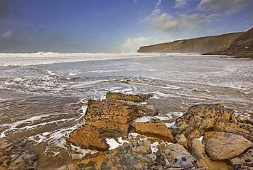 The sand, rocks, surf, cliffs and storm clouds of Cornwall's Atlantic coast, at Trebarwith Strand, near Tintagel, Cornwall, England, United Kingdom, Europe