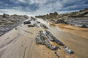 A rocky shore at low tide and under grey skies; at Welcombe Mouth, Hartland, north Devon, England, United Kingdom, Europe