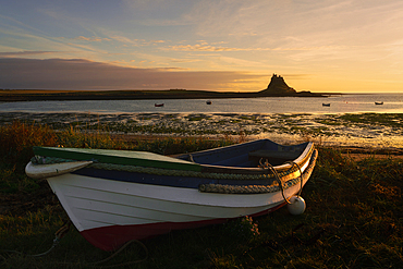 Boat on the shore of Holy Island with Lindisfarne Castle in the background, Northumberland, England, UK