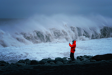 Man photographing sneaker waves, Reynisfjara Beach, Iceland, Europe