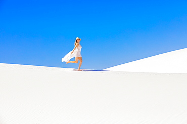 Woman walking across Gypsum Sand Dune, White Sands, New Mexico, United States of America, North America