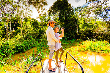 Couple searching for wildlife on a boat tour of the Amazon River, Peru, South America