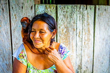 Woman and her rescued monkey at a local village on the Amazon River, Peru, South America