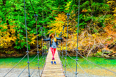 Woman taking in the scenery while crossing a bridge in Mount Rainier National Park, Washington State, United States of America, North America