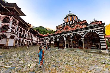 Woman walking towards Rila Monastery, UNESCO World Heritage Site, Bulgaria, Europe