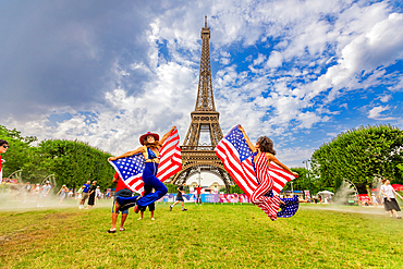 Patriotic American Woman jumping and cheering for Team USA and the Paris 2024 Olympics in front of the Eiffel Tower, Paris, France, Europe