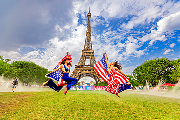 Patriotic American Woman jumping and cheering for Team USA and the Paris 2024 Olympics in front of the Eiffel Tower, Paris, France, Europe