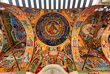 Horizontal, upward shot of the painted ceiling in the portico of the main church at Rila Monastery in Rila, Bulgaria, depicting detailed Orthodox Christian frescoes with religious scenes and figures.