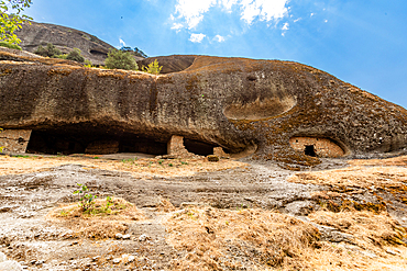 Wide view of the Hermit Caves, or Badova, showing multiple rock-cut entrances used by monks for seclusion and meditation, Meteora, Thessaly, Greece.