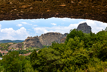 Landscape view from the Hermit Caves, also known as Badova, looking out toward the rock formations and monasteries of Meteora, framed by the cave’s rocky overhang, Thessaly, Greece.