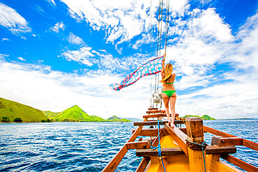 Girl perched on bow of Phinisi Boat, sailing through Komodo National Park, Indonesia, Southeast Asia, Asia